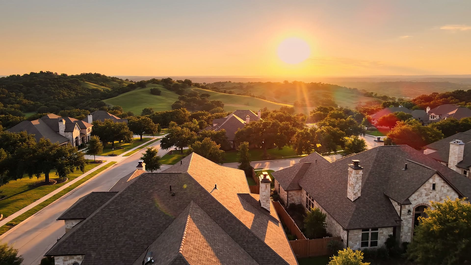 Aerial view of an Austin Hill Country neighborhood at golden-hour sunset